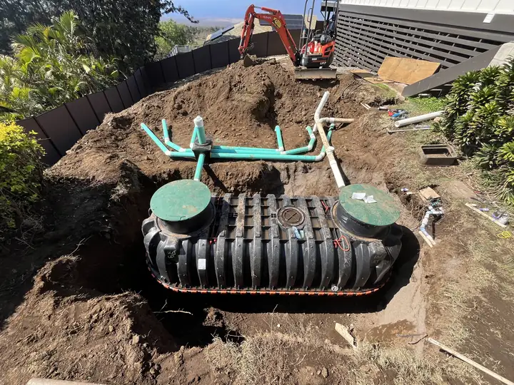 New septic tank set in its excavation with inlet and outlet piping connected, before backfill